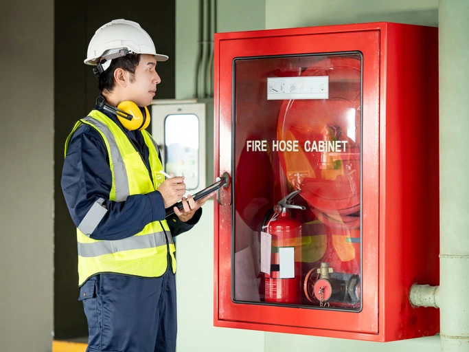 Building inspector man using digital tablet checking fire hose cabinet